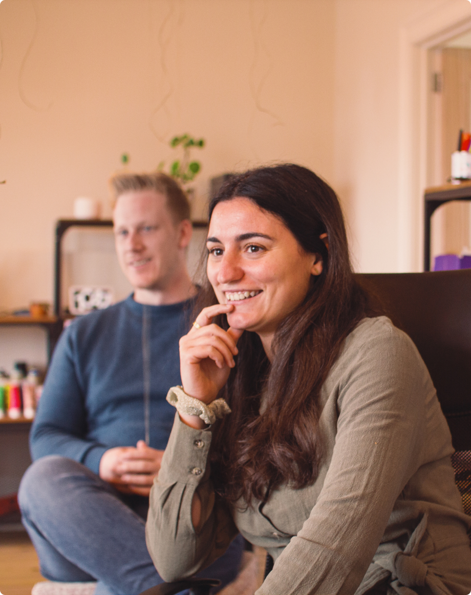 Two colleagues (a guy and a girl) looking towards the camera while sitting in the office