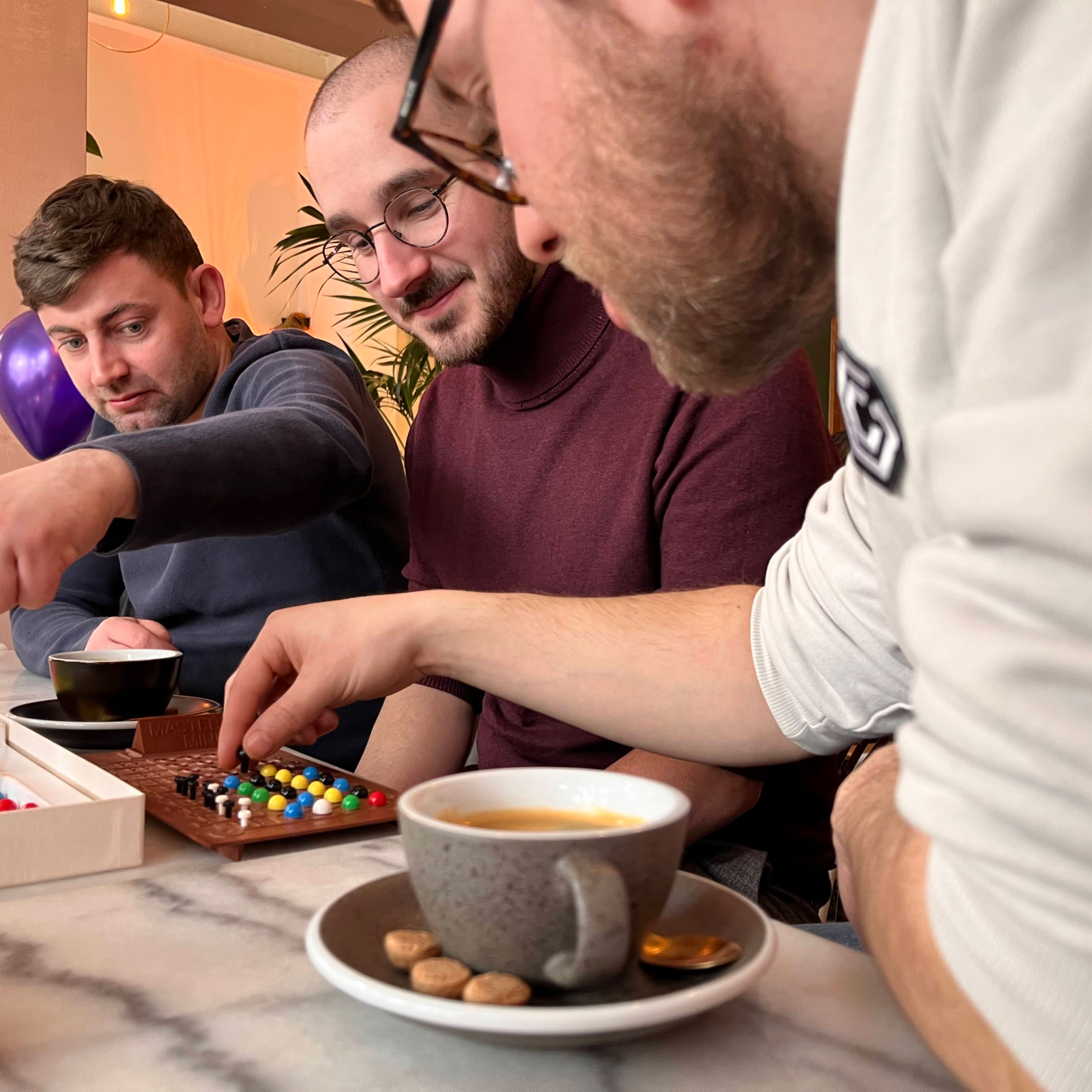 Three colleagues playing mastermind together at a table